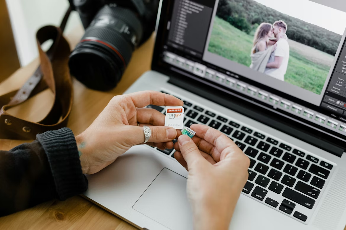 Photographer transferring image files from a memory card to a laptop, illustrating how artists can protect digital content from AI scraping with Nightshade data poisoning techniques