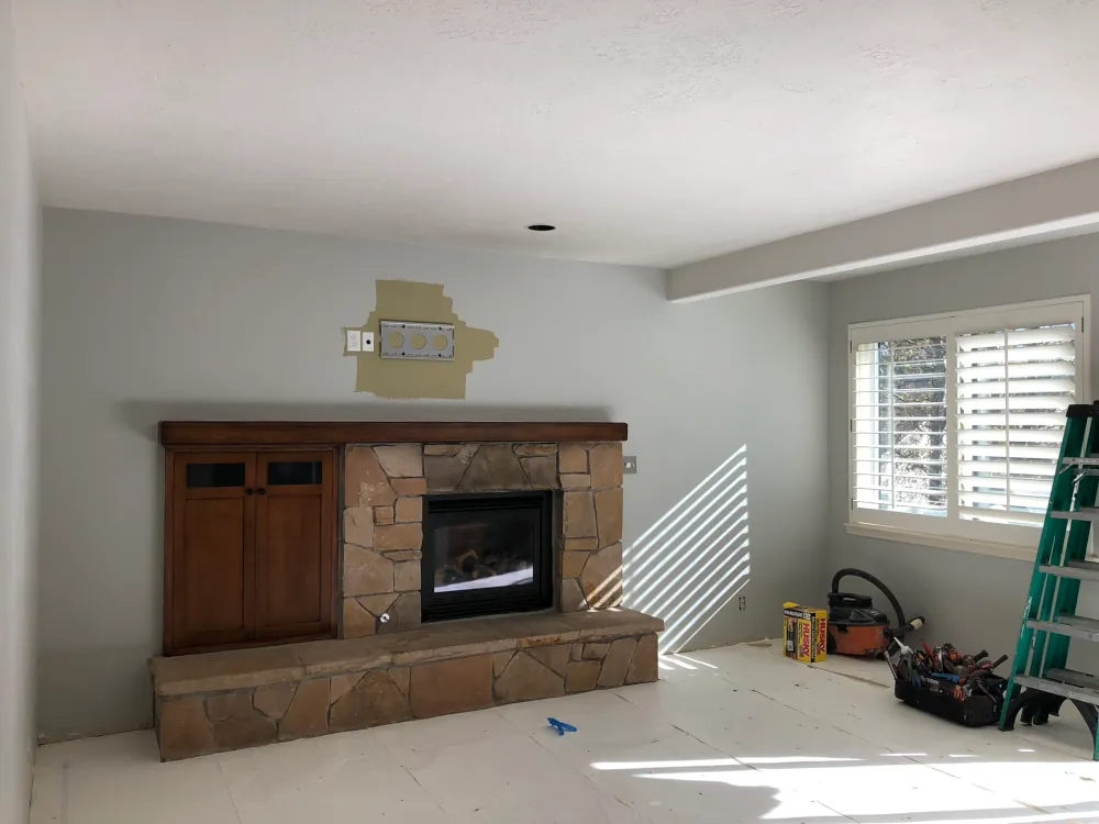Living room before whole house remodel in Salt Lake City showing stone fireplace, wood cabinet, and unfinished walls during renovation prep