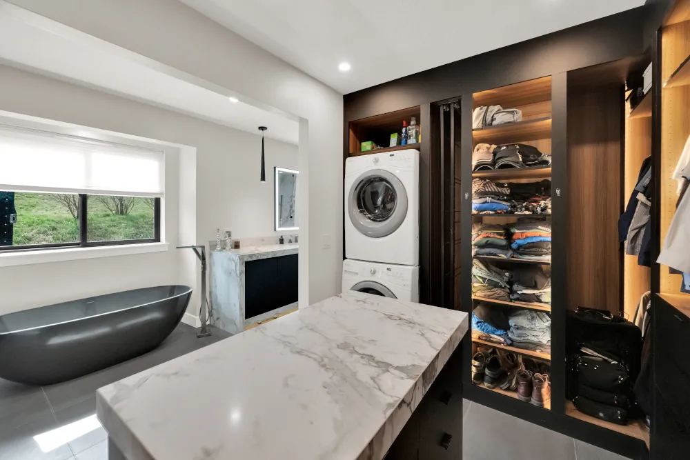Custom walk-in closet with backlit wood shelving, a marble-topped island, and integrated laundry