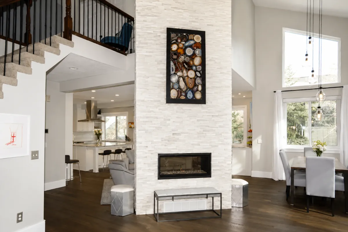 Two-story stacked white stone fireplace with a linear gas insert in an open-concept living area
