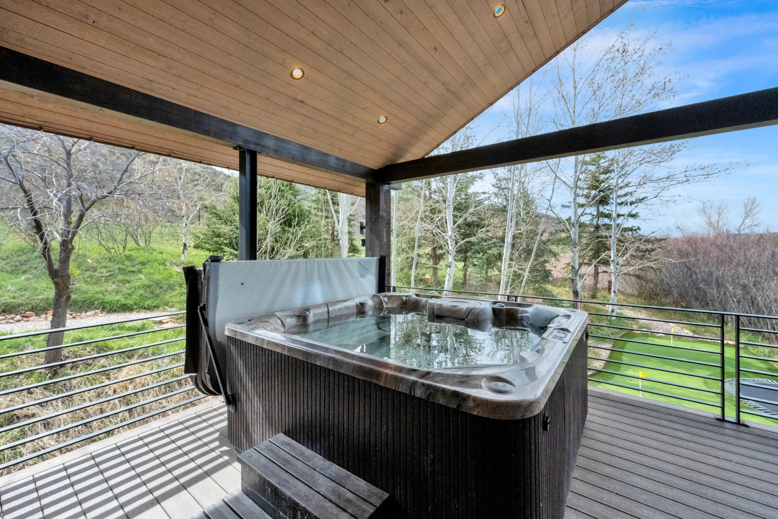 Exterior remodel with covered deck, hot tub, and cable railing overlooking backyard