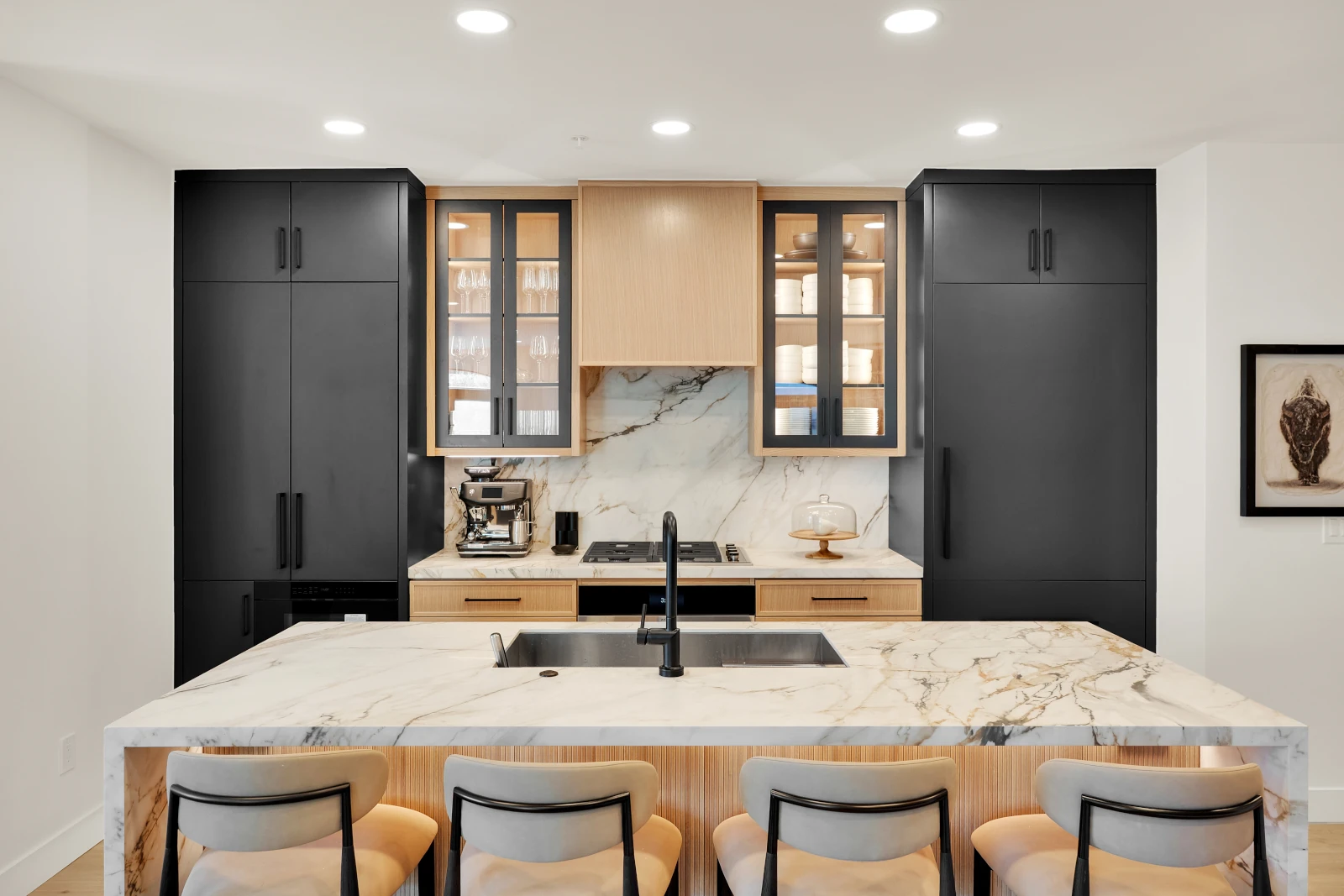 Kitchen remodel with black and white oak cabinets, waterfall marble island, and bar seating