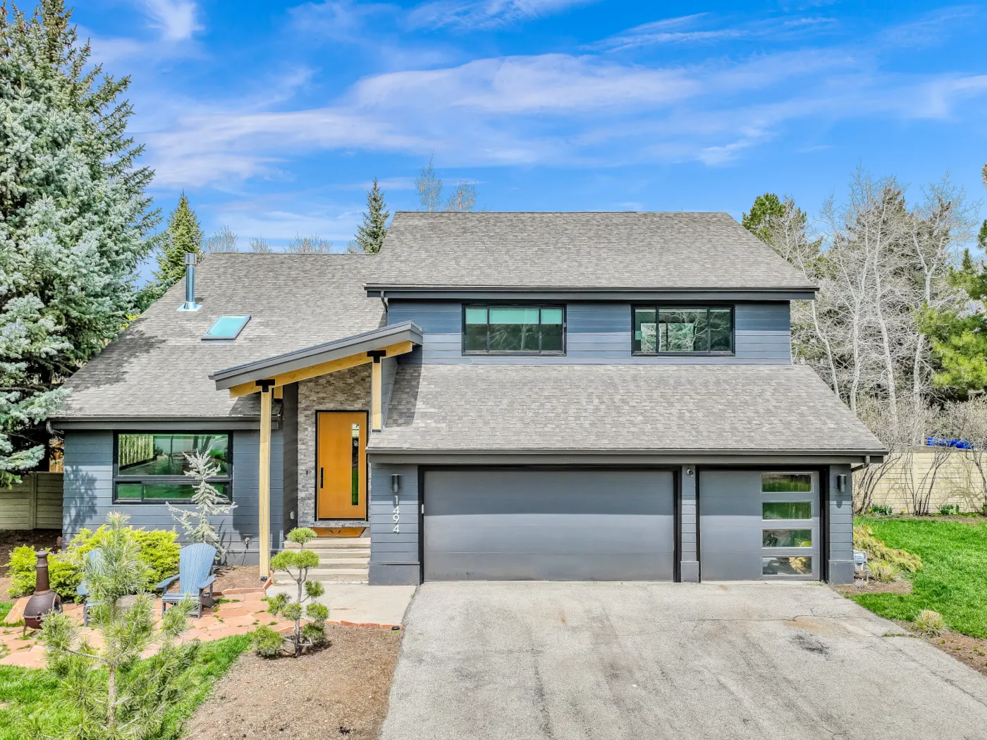 Exterior remodeling with gray lap siding, stone entry, new roof, and modern garage doors