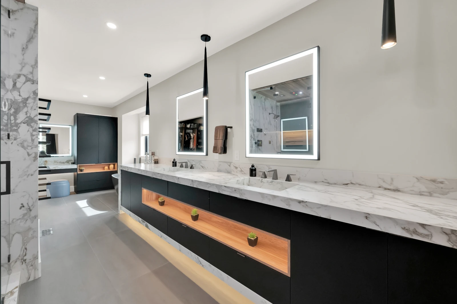 Luxury primary bathroom with double marble vanity, black floating cabinets, backlit LED mirrors, and marble walk-in shower