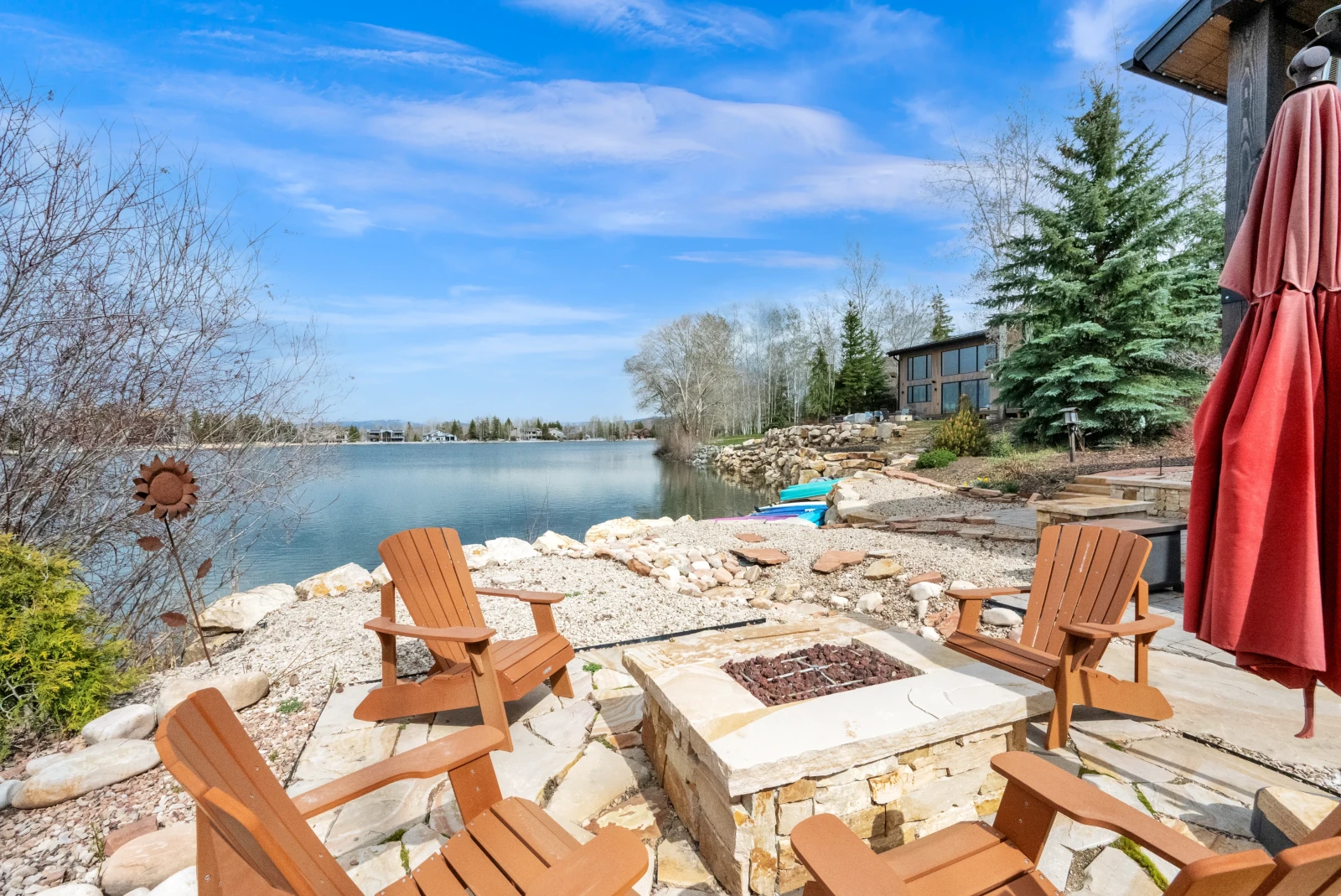 Lakeside flagstone patio with stone fire pit and Adirondack chairs
