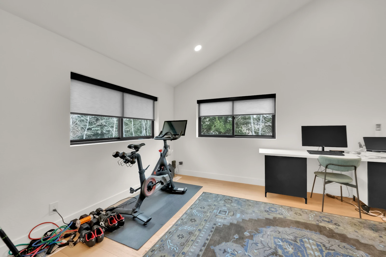 Home gym and office with built-in desk and vaulted ceiling