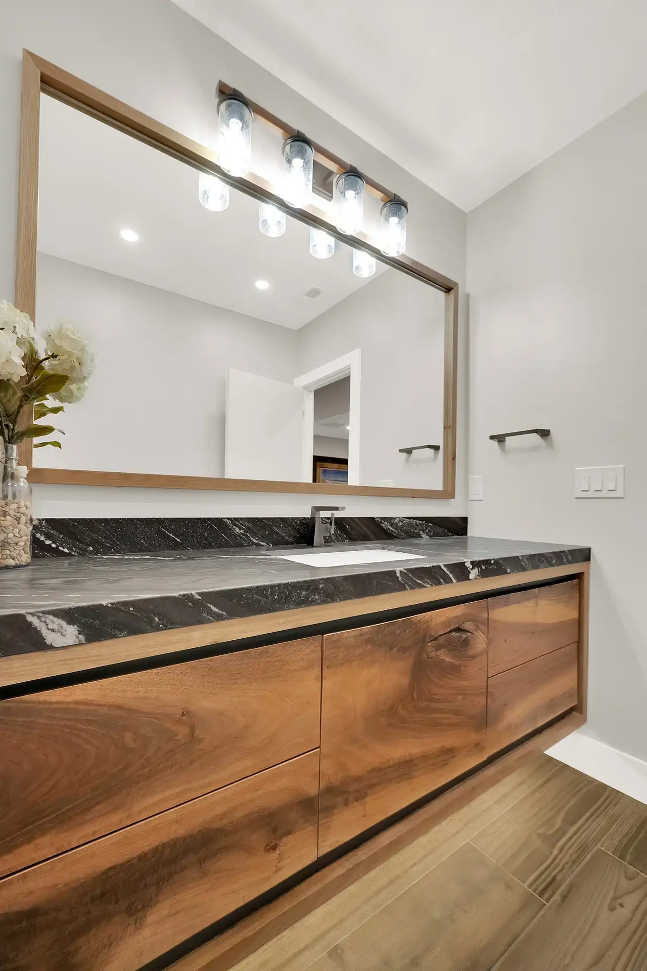 Bathtub with natural stone tile flooring and large custom cabinetry