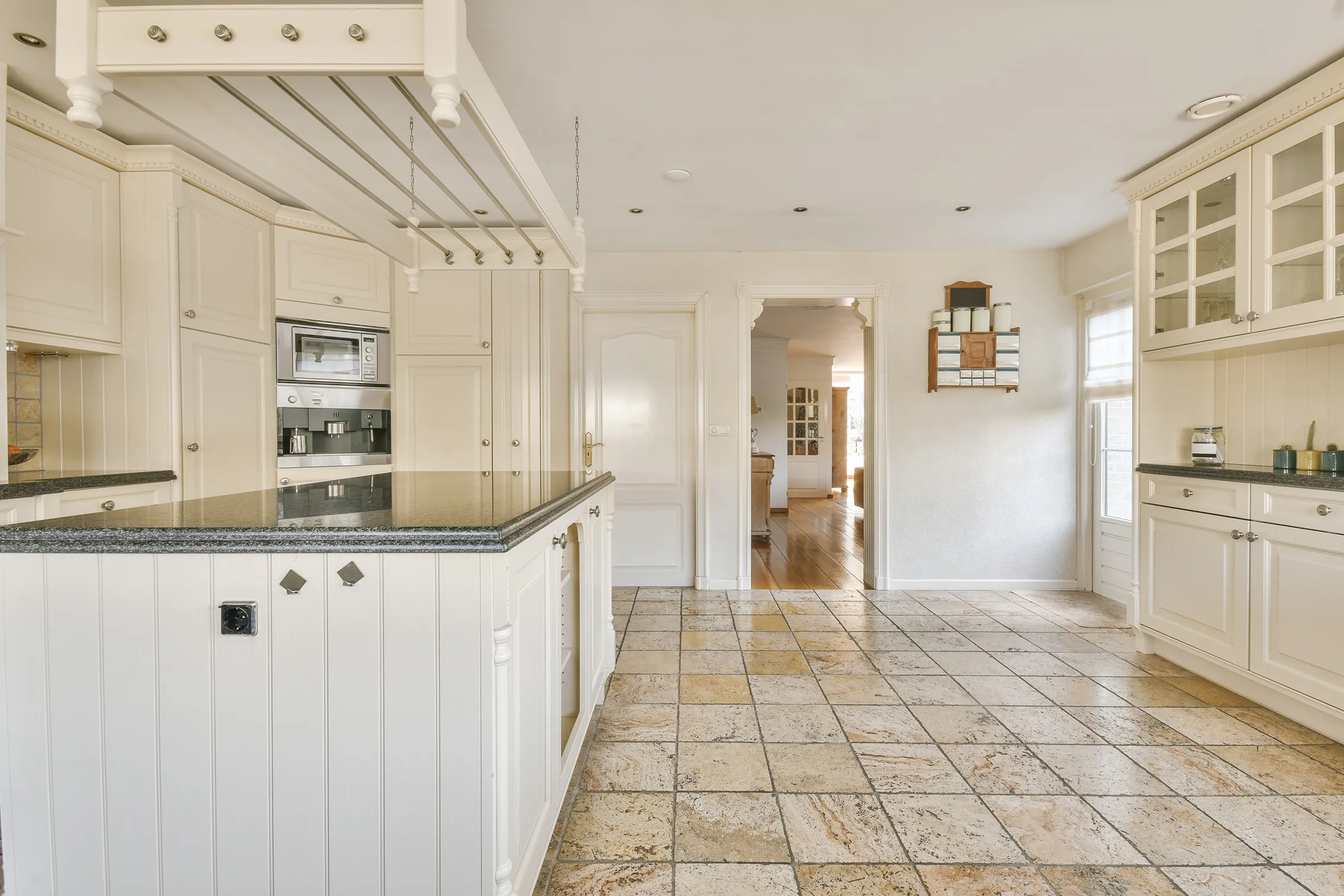 Rustic polished natural stone tile kitchen flooring in a classic cream-colored kitchen.