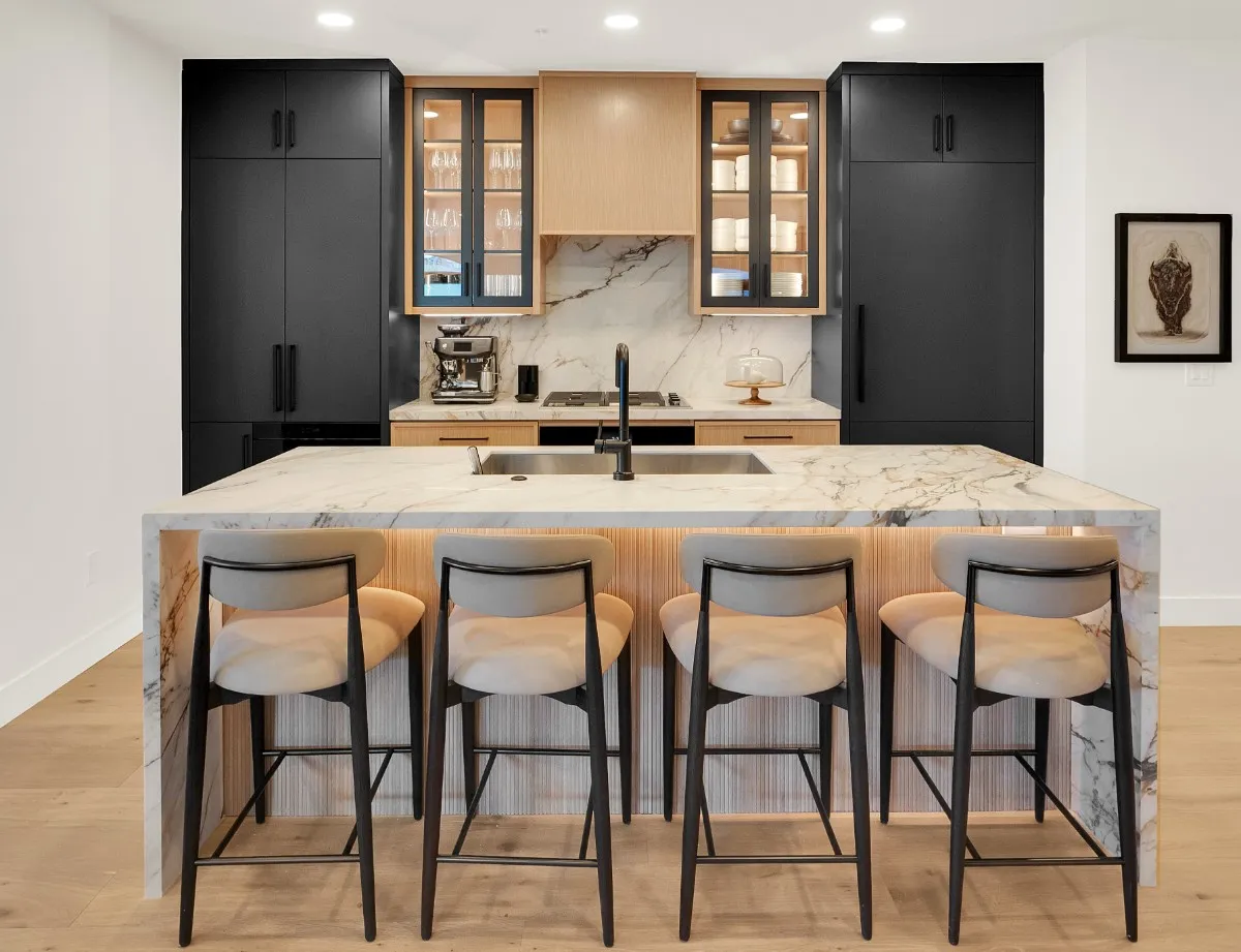 Black tall cabinets and a glass-front display cabinet above a quartzite countertop