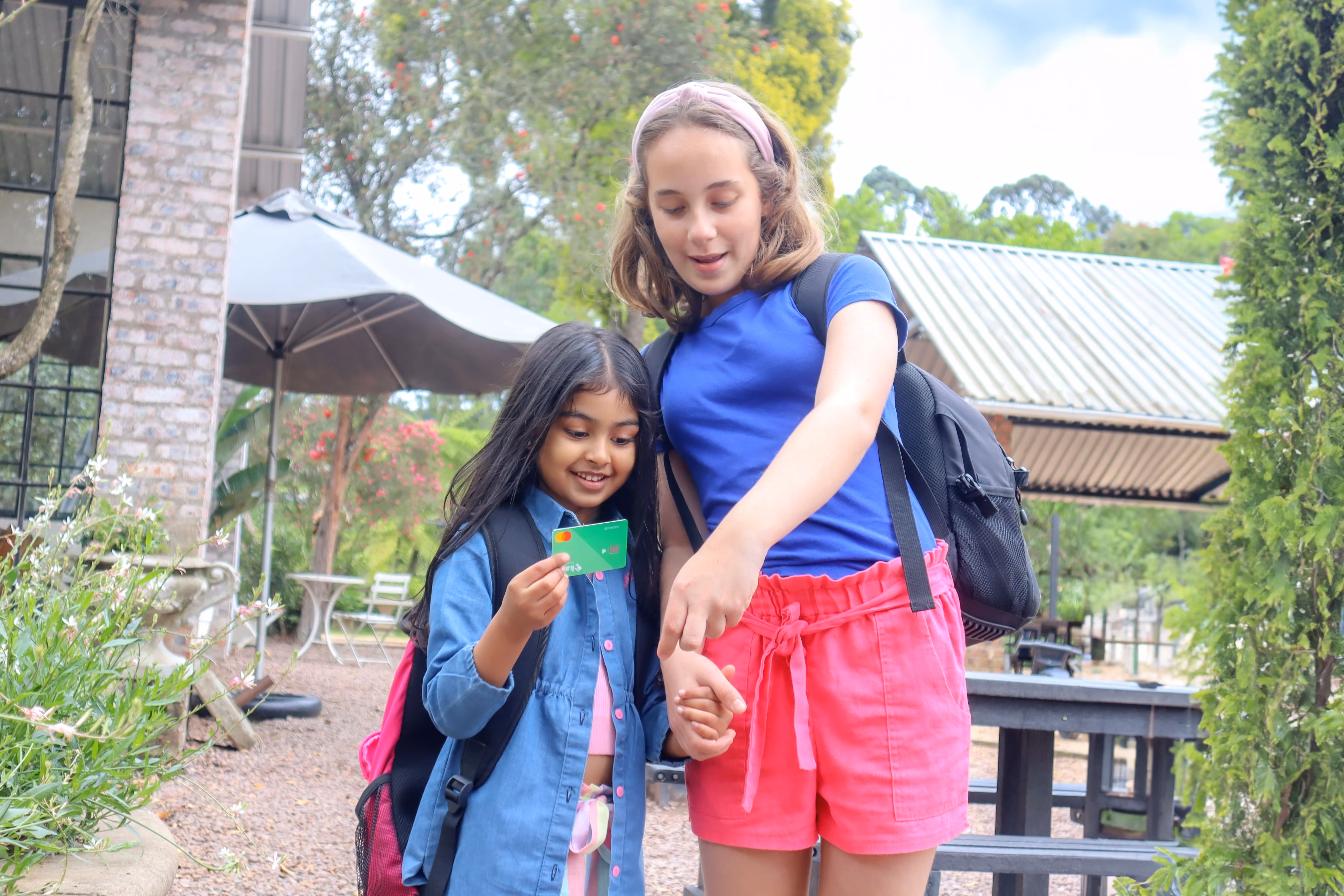 2 girls walking and holding hands with a Karri Card