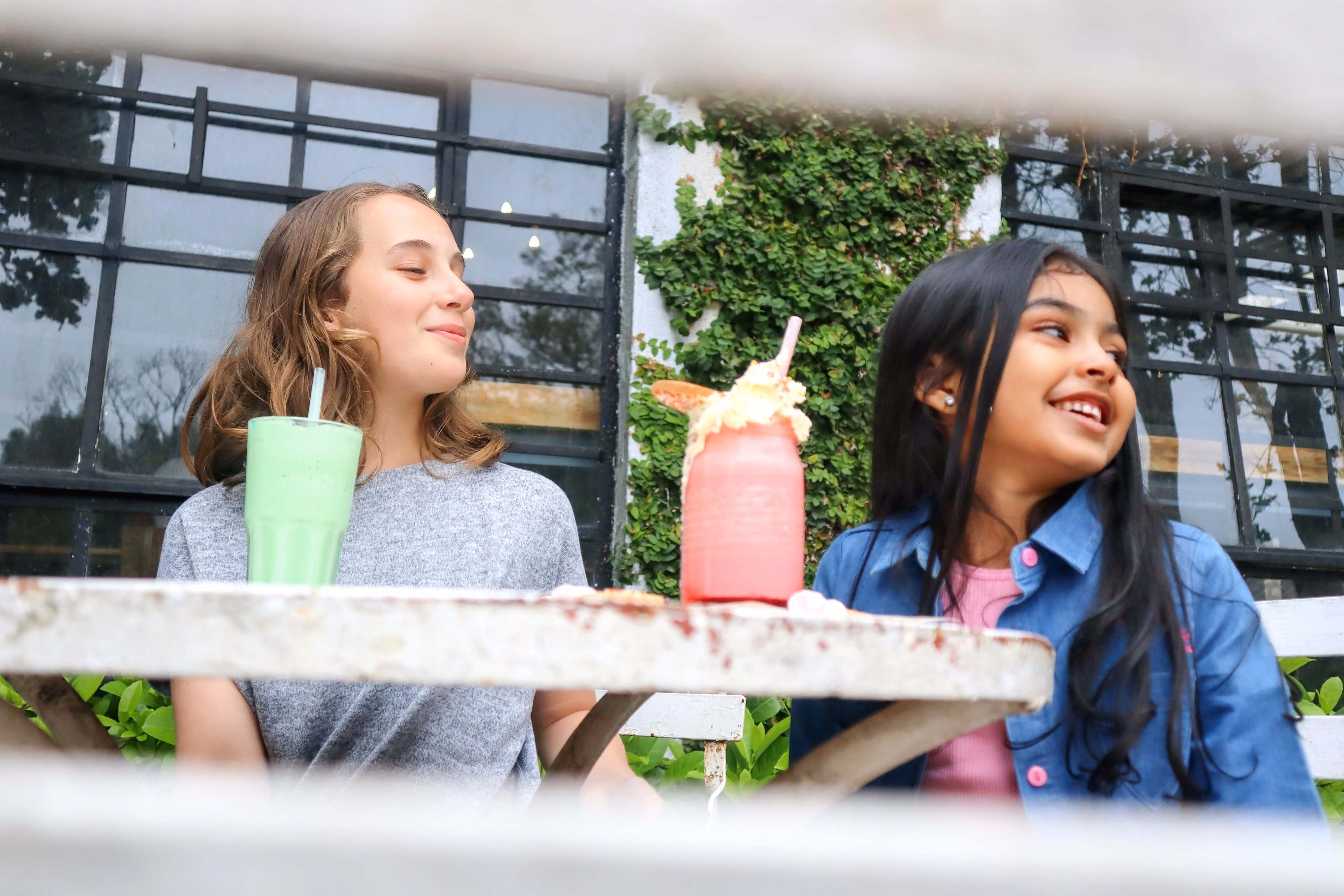 2 Girls sitting together drinking milkshakes