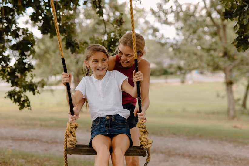 Lady smiling and pushing her daughter on a swing