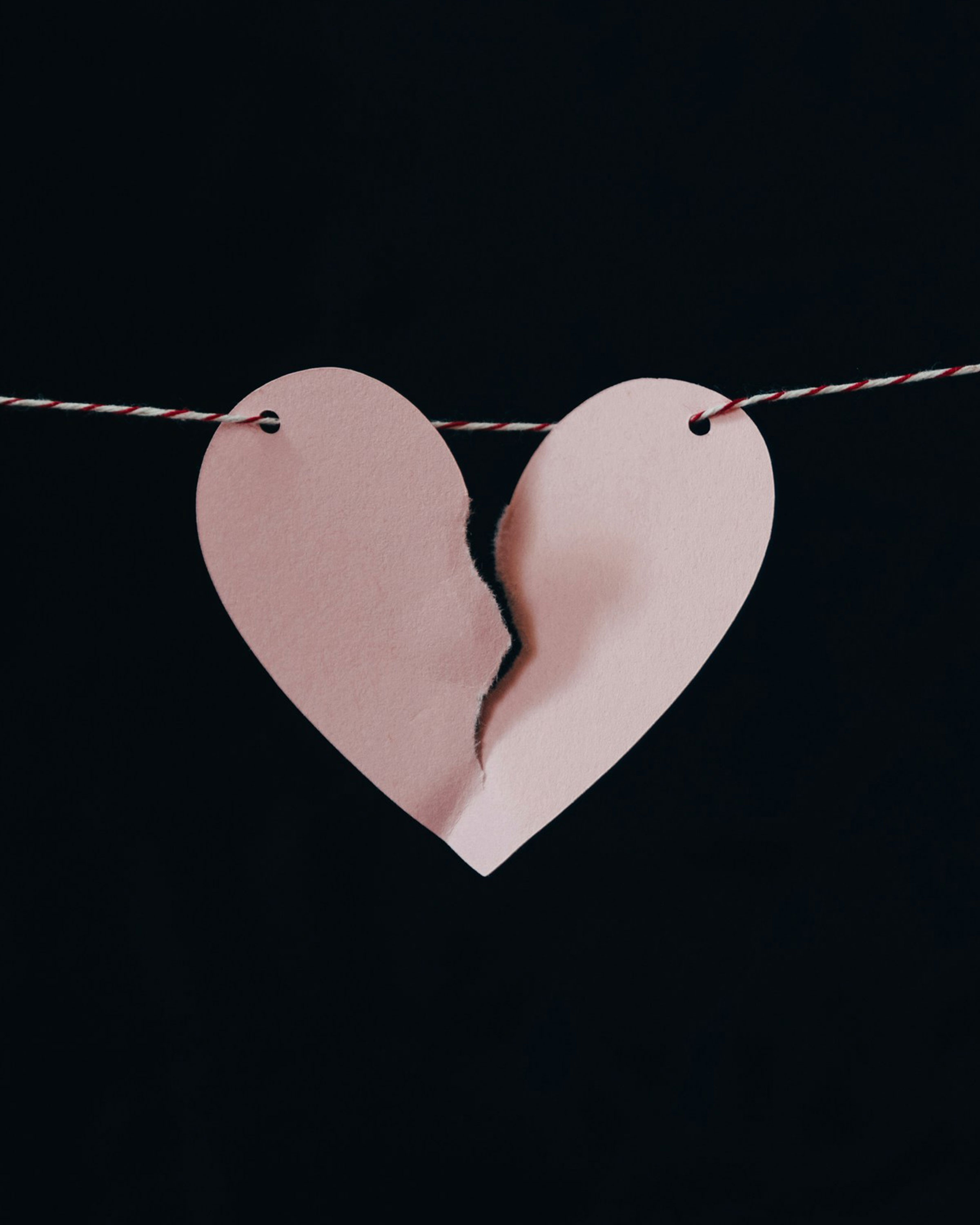 Pink paper heart ripped in half.