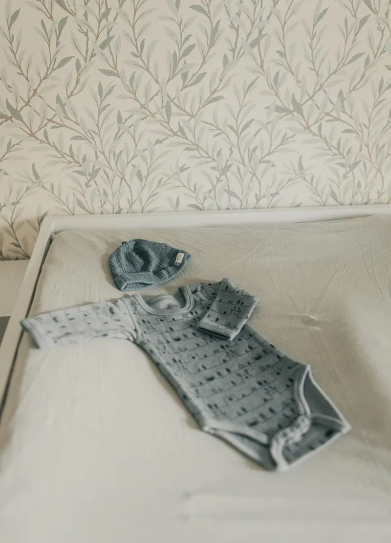 Langarm-Body und Mütze für Baby auf einem Wickeltisch