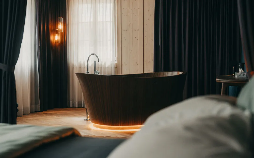 Dunkle Vorhänge neben Holzwänden in einem Zimmer mit freistehender Badewanne