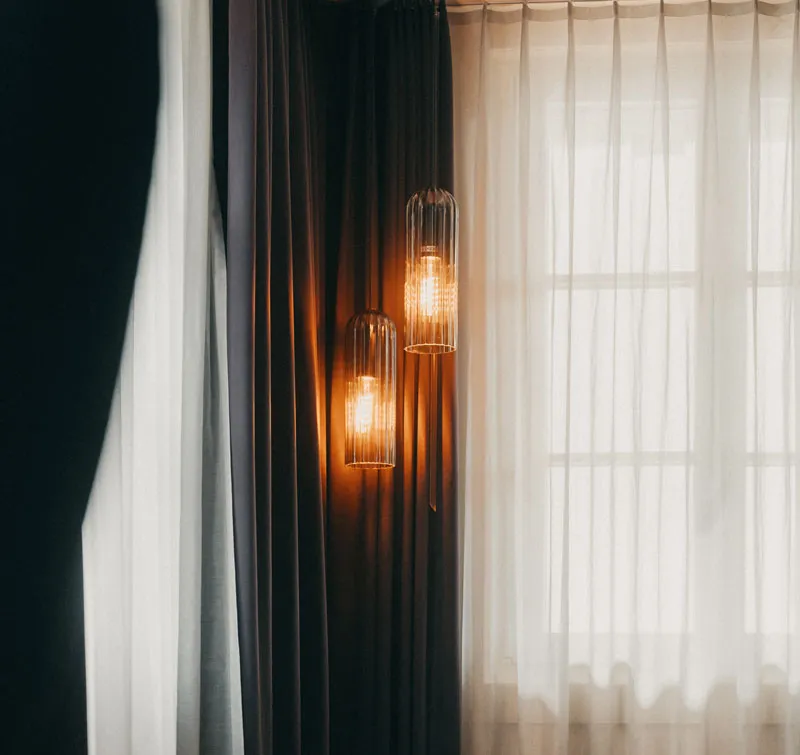 Hängende Lampen in einer Ecke vor abdunkelnden und durchscheinenden Vorhängen