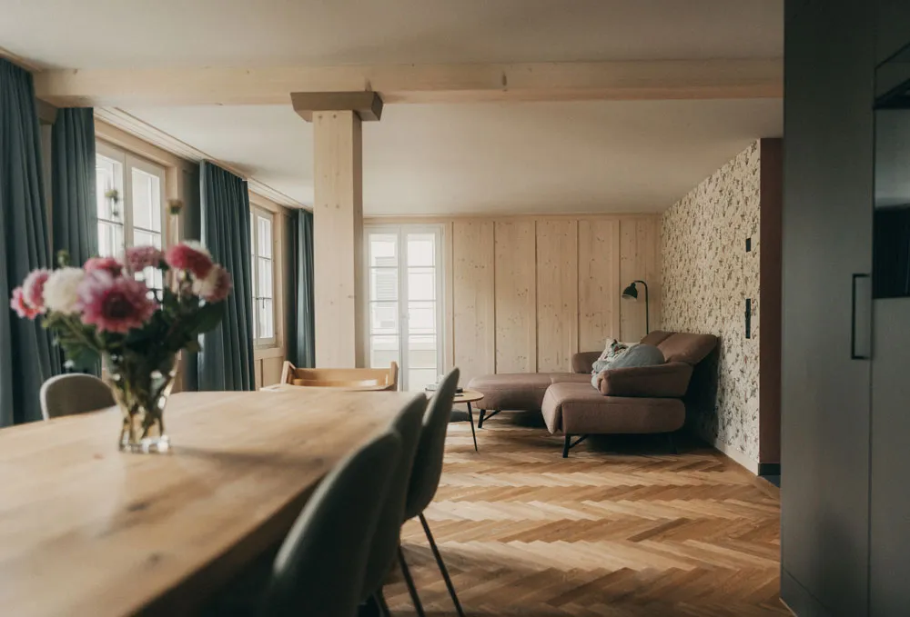 Aufenthaltsbereich mit Holztisch, Stühlen und Sofa im Geburtshaus am Mülibach
