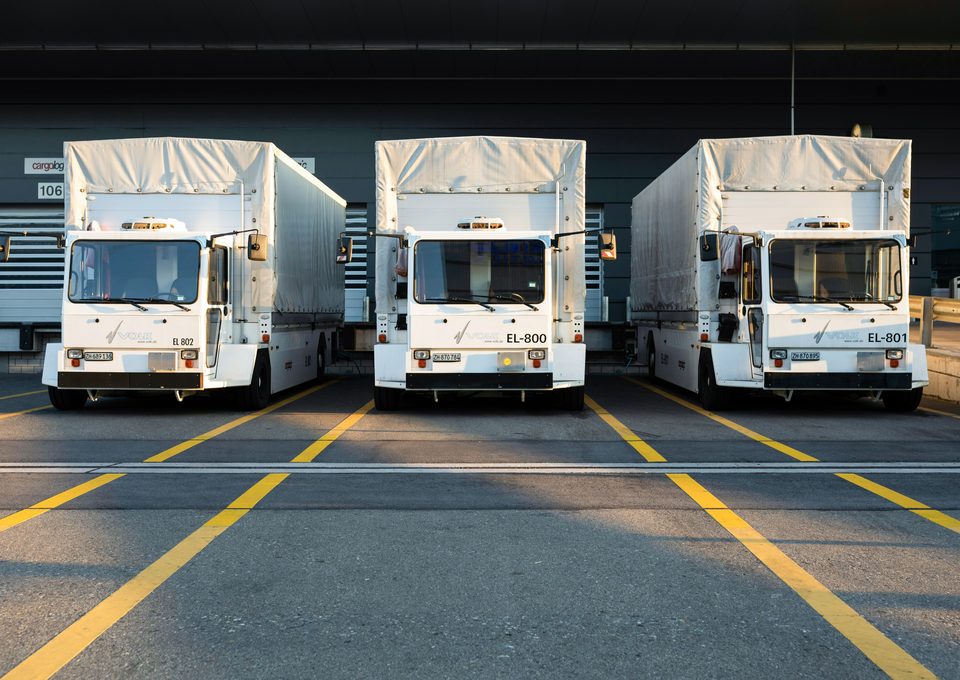 Three white trucks parked at a depot