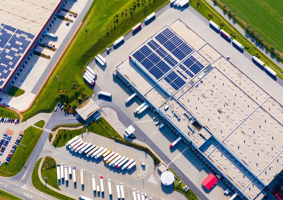 Aerial view of a distribution center with solar roofs and trucks