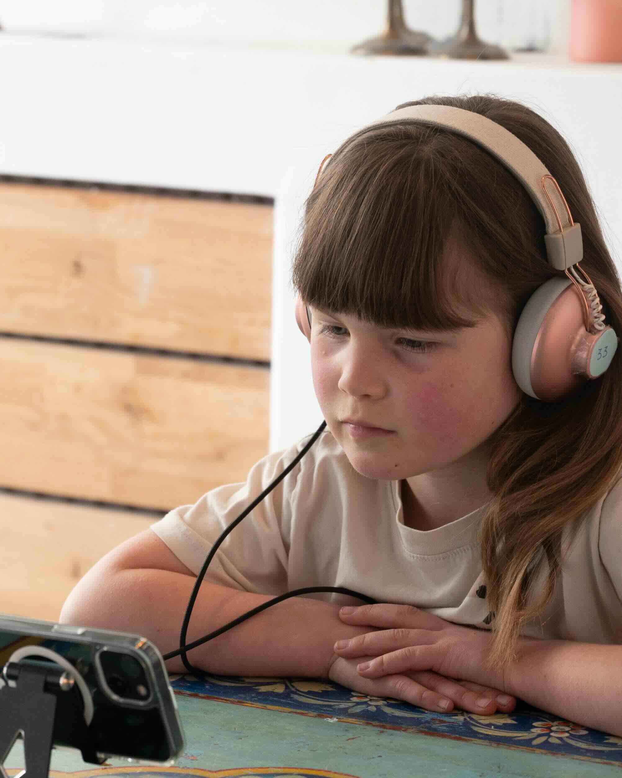 a girl with headphones watching a video on an iPhone