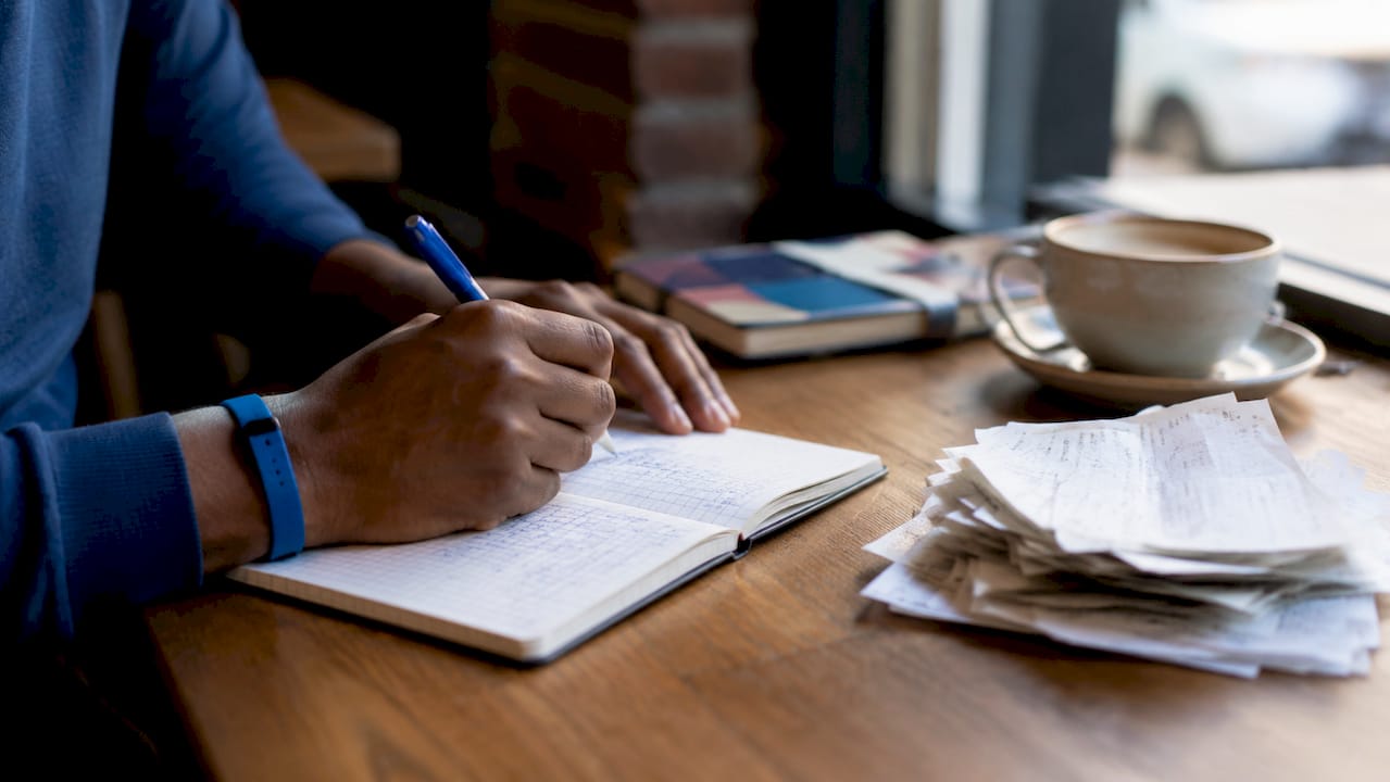 Hands taking notes on trucking expenses