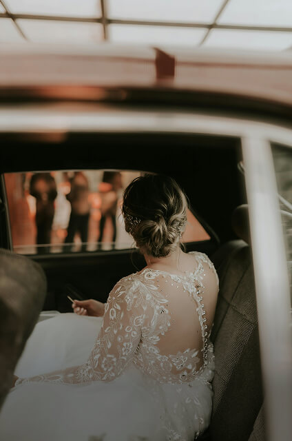 woman in wedding dress sitting in car