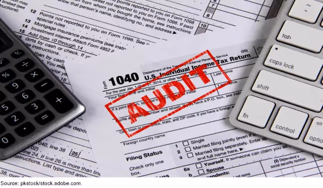 Tax form 1040 with calculator and keyboard, marked with red audit stamp