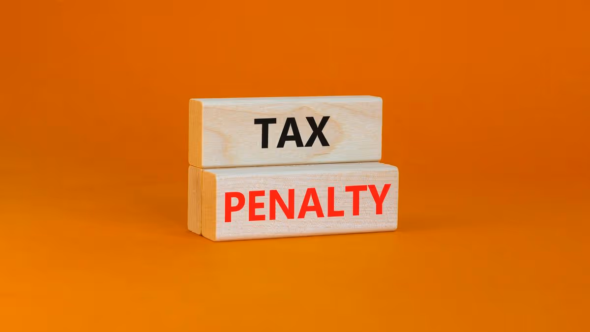 Wooden blocks spelling out tax penalty on orange background