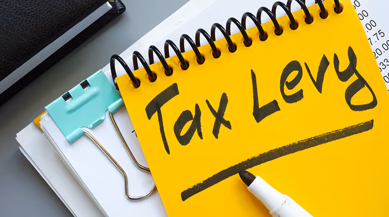 Yellow notepad with "Tax Levy" written, paperclip and marker nearby