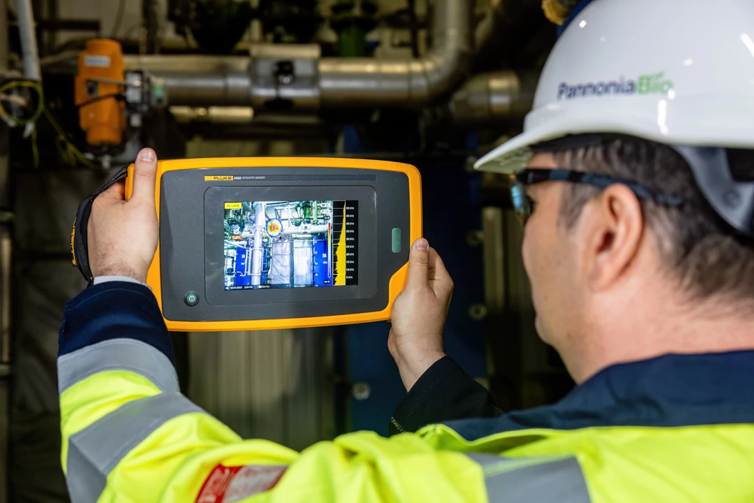 Engineer in a hard hat checking plant equipment with an acoustic imaging camera