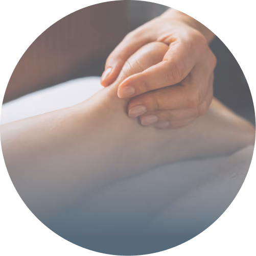 Hands giving a gentle foot massage on a foot resting on a white surface.