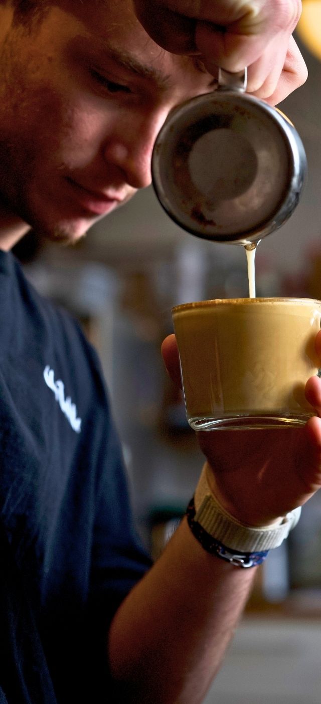 A man pours a coffee at The Table Coffee Shop Cardiff.