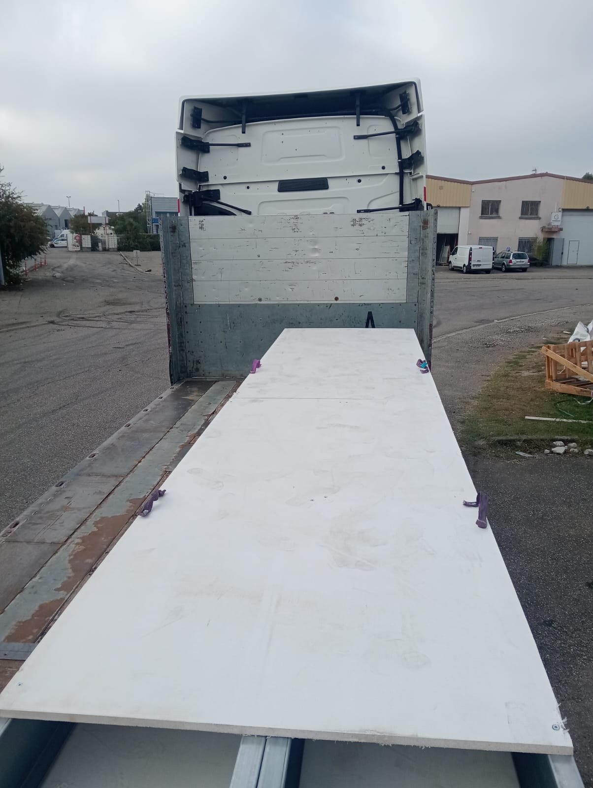 Panneaux d'ossature métallique légère sanglés sur le plateau du camion avant le départ vers le chantier