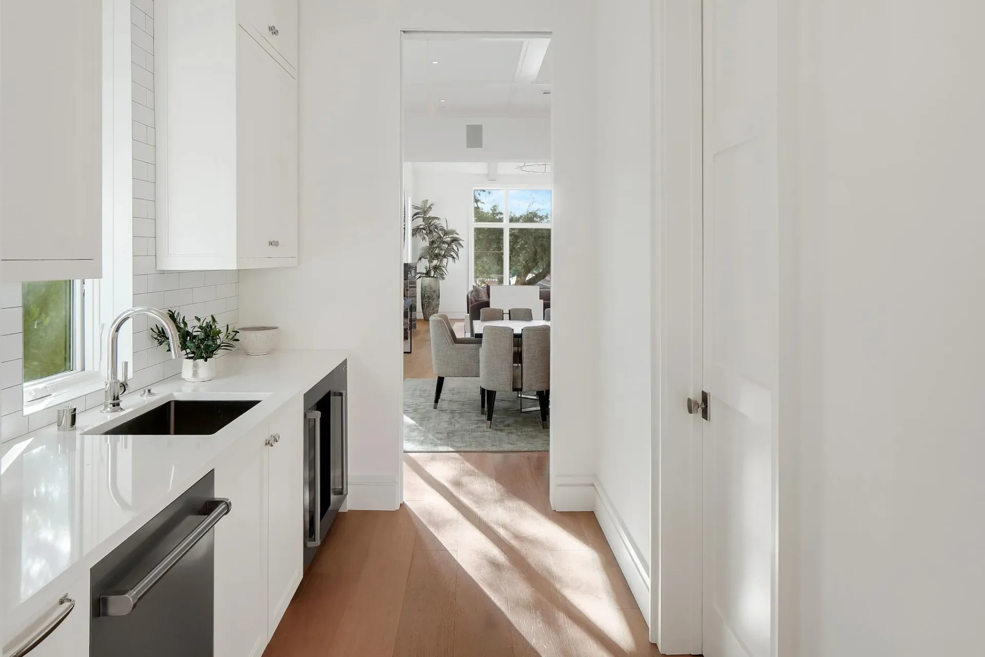 South Bundy pantry with white cabinetry, a sink below the window and a view through to the dining room.