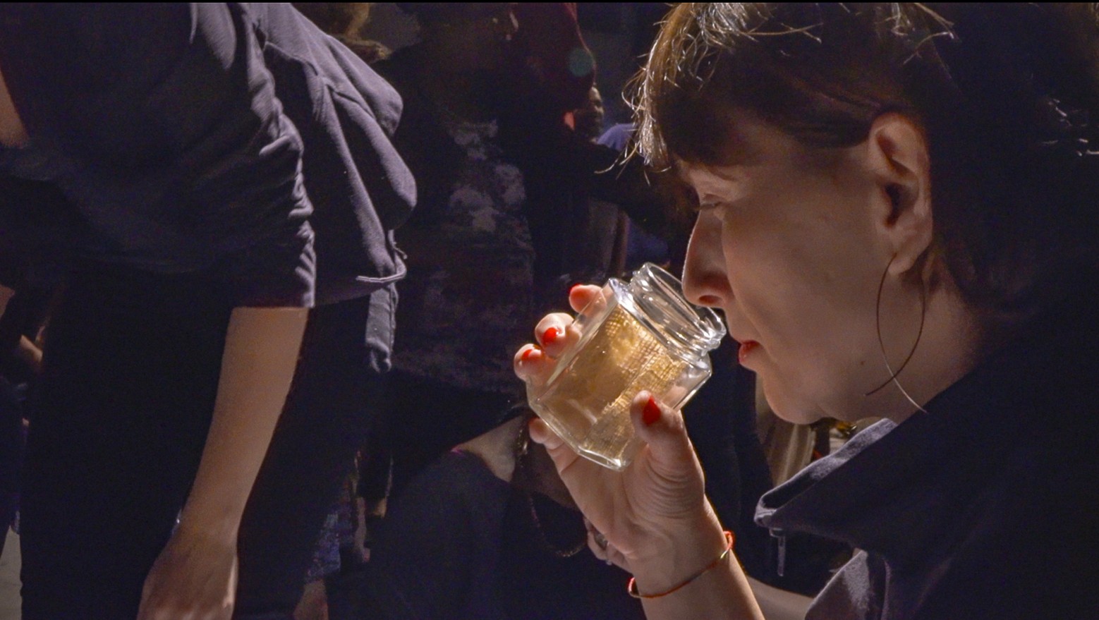 Audience members smelling the inside of a glass jar
