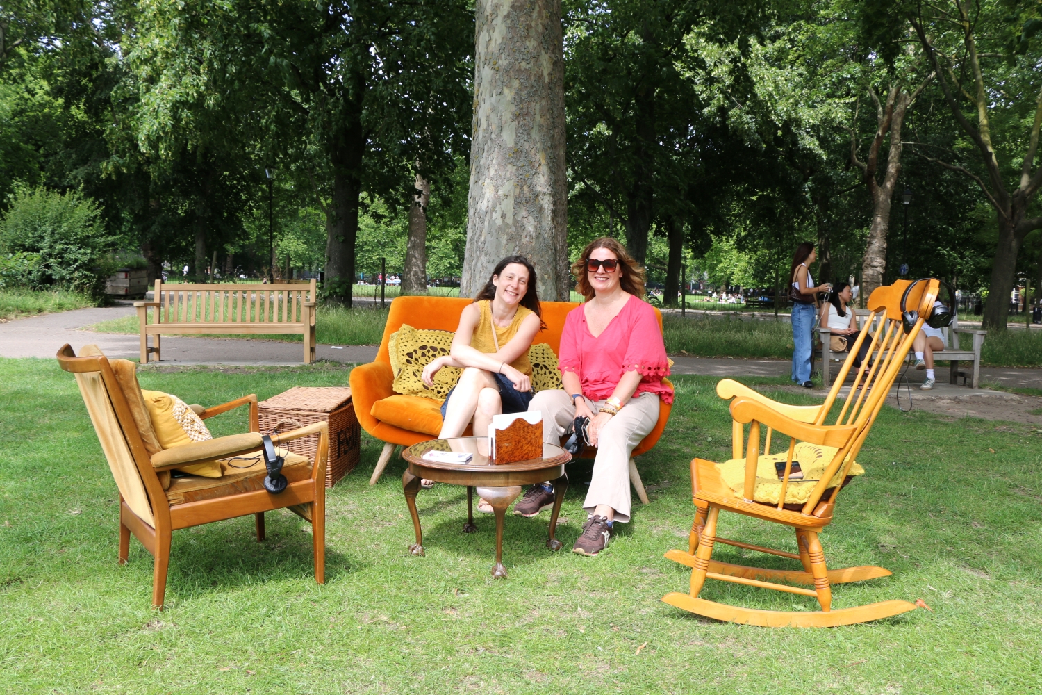 Two women sitting in an outdoor living room in a park