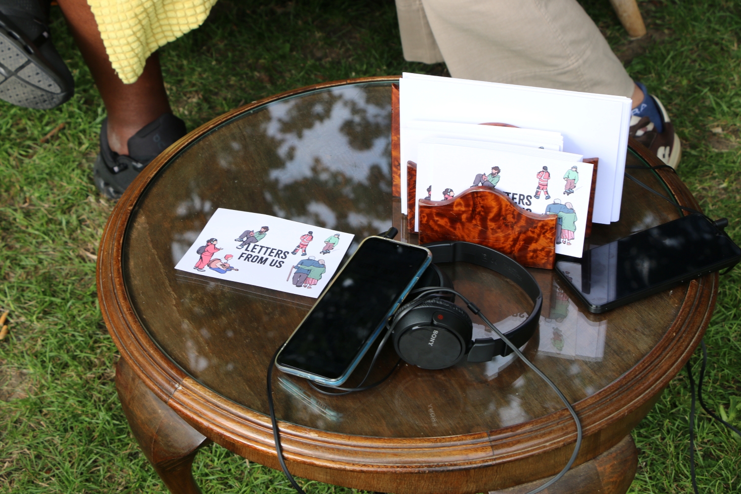 A smartphone, headphones and a postcard marked 'Letters from us' on an old coffee table