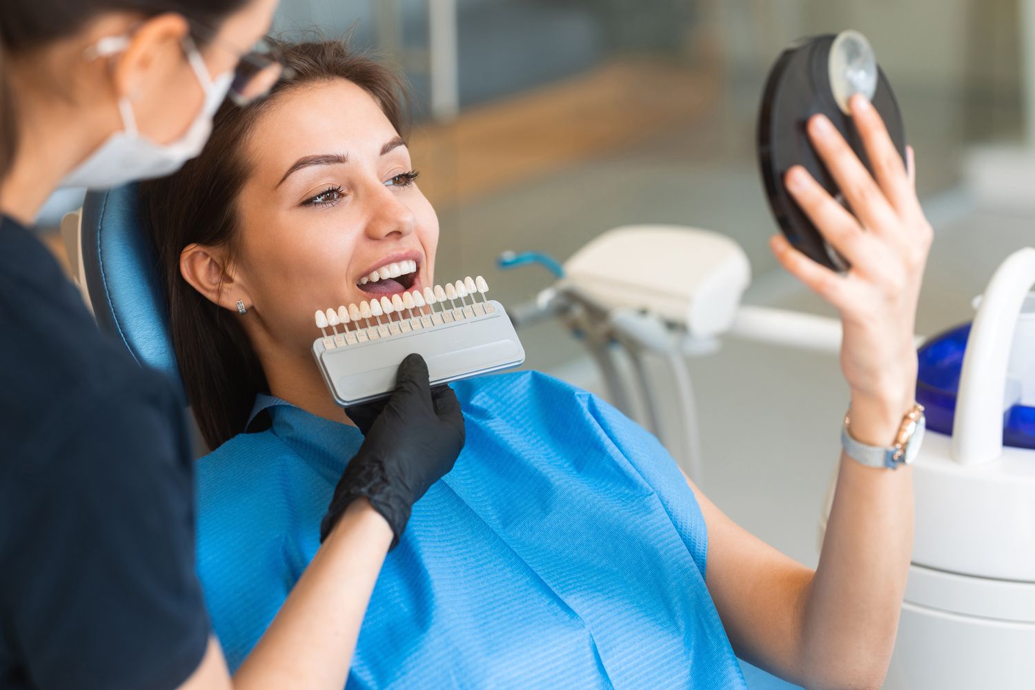 Dentist gently placing a porcelain veneer onto a patient’s tooth