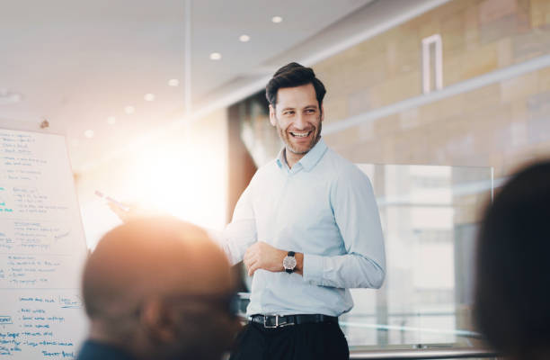 A man presenting during a meeting, smiling widely and confidently.