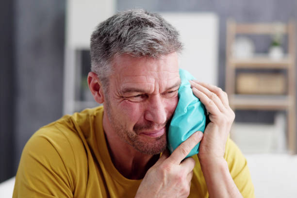 Upset Man Touching Cheek With Cold Water Bag Upset Man Touching Cheek With Cold Water Bag At Home Adult applying a cool compress to their jaw stock pictures, royalty-free photos & images