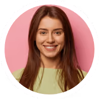 Smiling young woman with long brown hair wearing a light green top against a pink background.