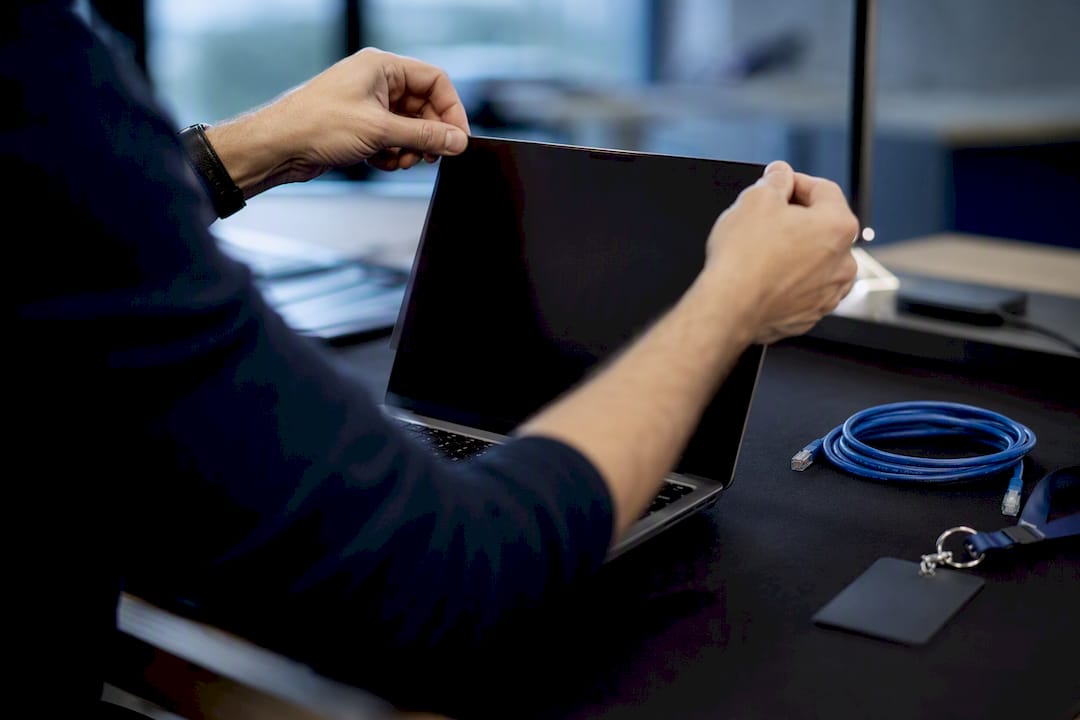 Hands adjusting privacy shield on device