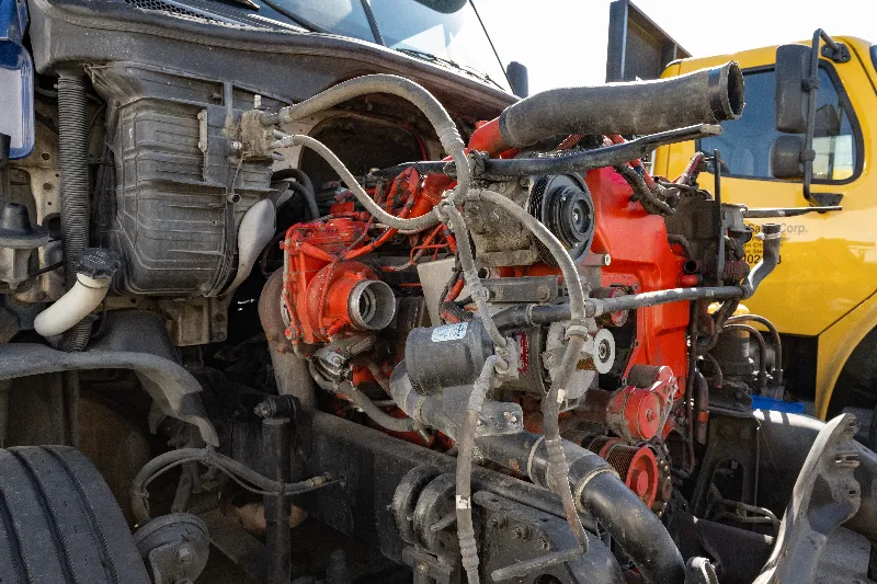 Partially disassembled red diesel engine in semi-truck chassis, with hoses and wiring exposed.