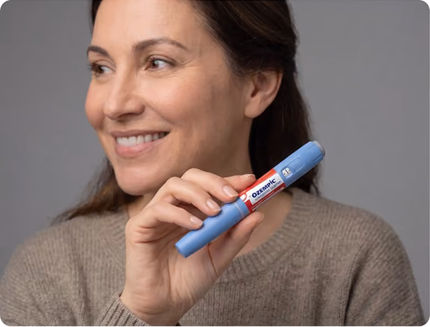 Smiling woman with curly hair holding a small vial labeled 'ivy GLP-1 Injection Rx only' against a teal background.