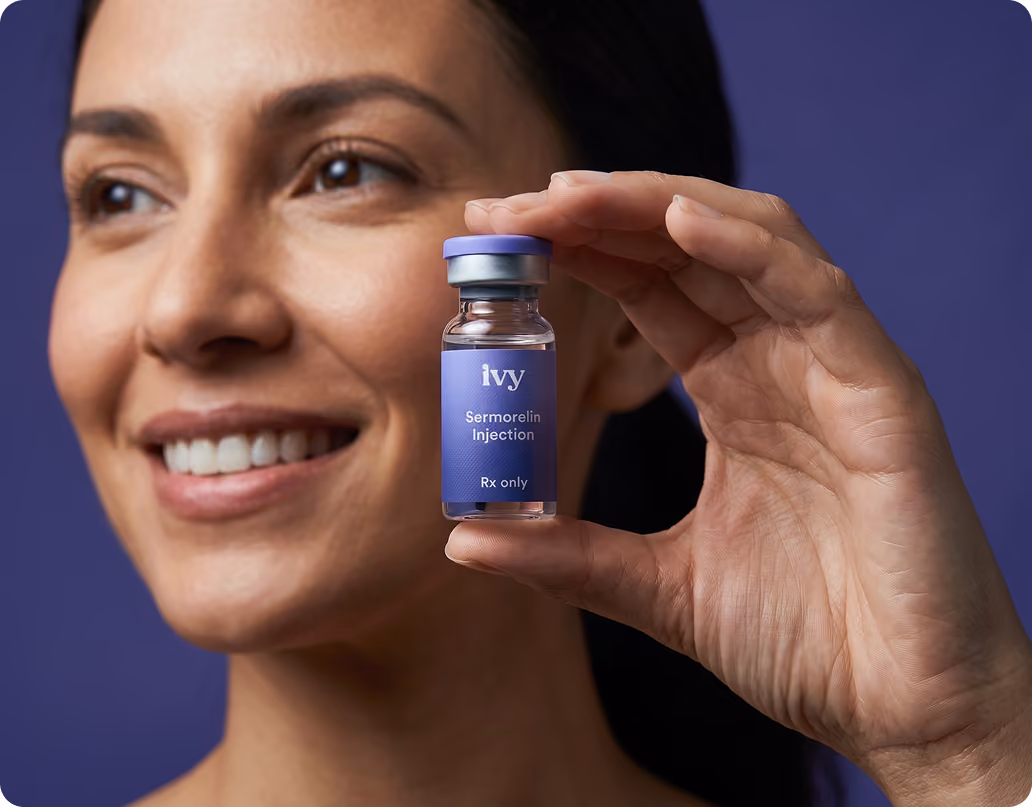 Smiling woman with curly hair holding a small vial labeled 'ivy GLP-1 Injection Rx only' against a teal background.