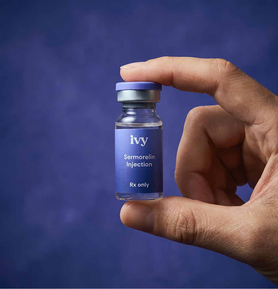 Hand holding a small vial labeled Ivy Sermorelin Injection Rx only against a blue background.