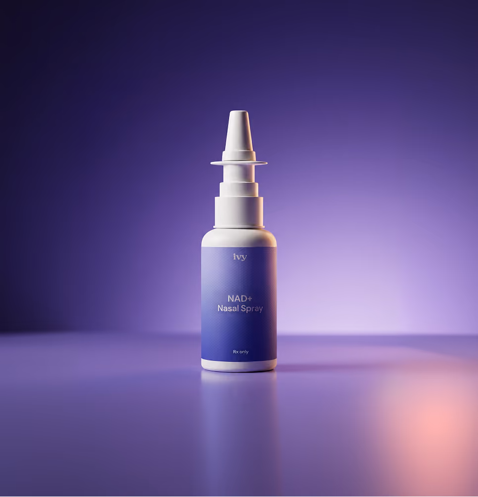 White nasal spray bottle with purple label reading 'NAD+ Nasal Spray' on reflective surface.
