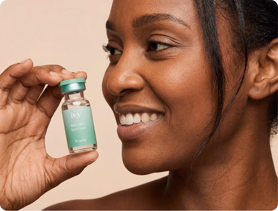 Smiling woman with curly hair holding a small vial labeled 'ivy GLP-1 Injection Rx only' against a teal background.