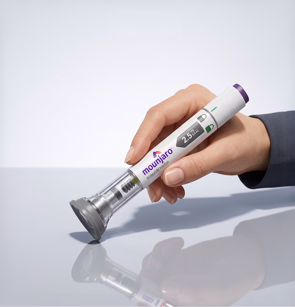 Hand holding a Mounjaro tirzepatide injection pen showing dosage 2.5 mg 0.5 mL with a gray and purple cap.