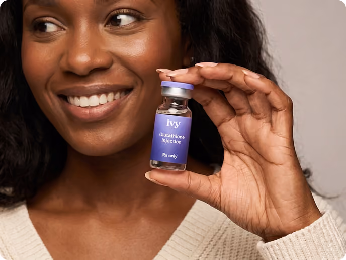 Smiling woman with curly hair holding a small vial labeled 'ivy GLP-1 Injection Rx only' against a teal background.